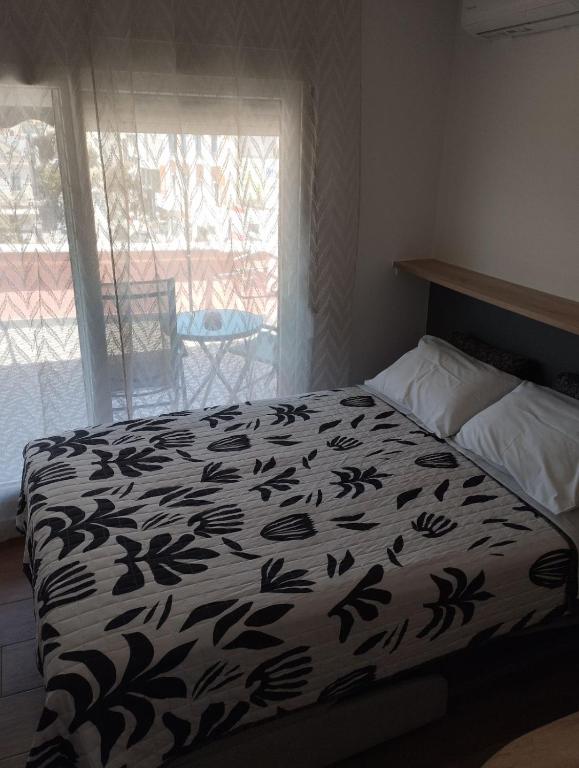 a bed with a black and white comforter and a window at Aquamarine Centrale in Kavála