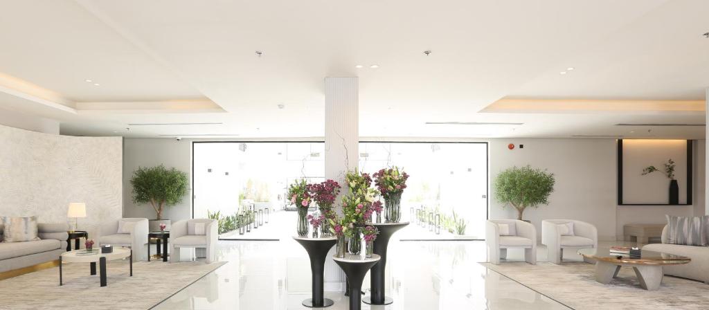 a lobby with white chairs and tables and flowers at Bawabat Alnakhil For Hotel Apartments in Riyadh