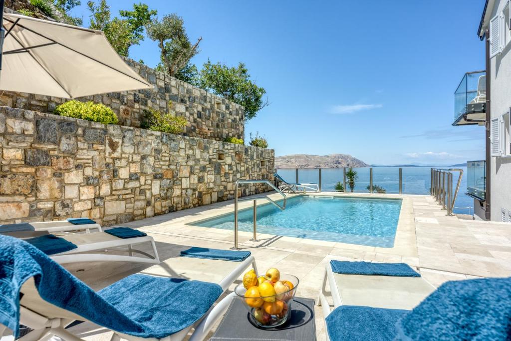 a villa with a swimming pool with chairs and an umbrella at 2Bfree Apartments in Stinica