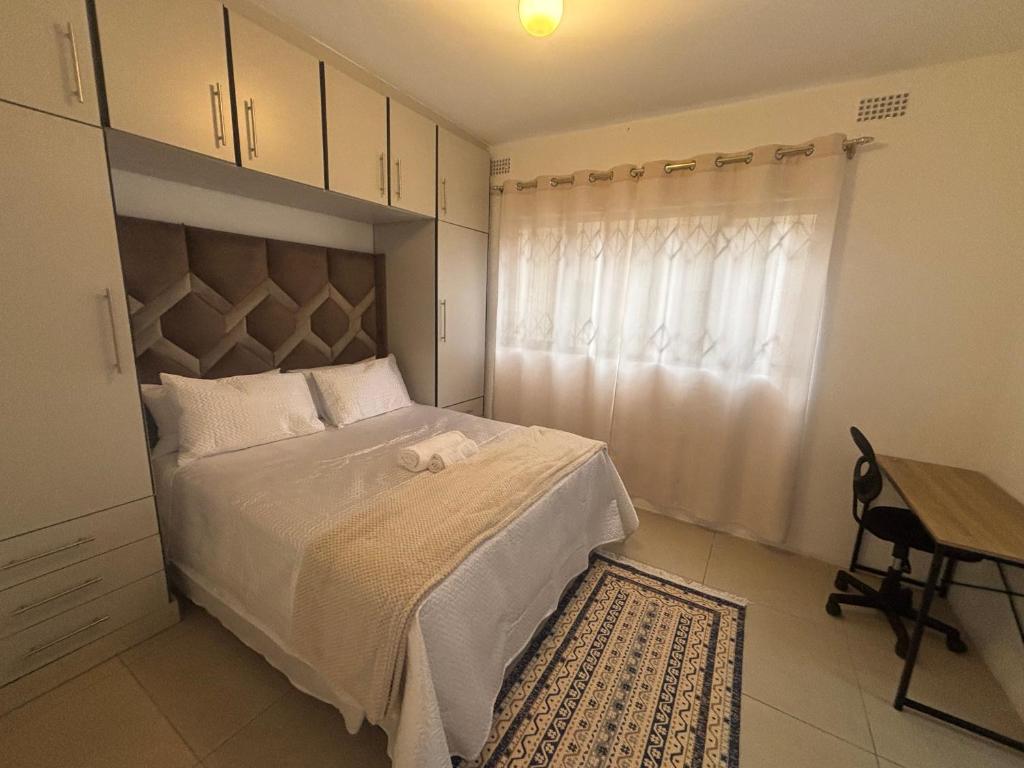a bedroom with a bed and a window and a table at Crescent Bud in Durban
