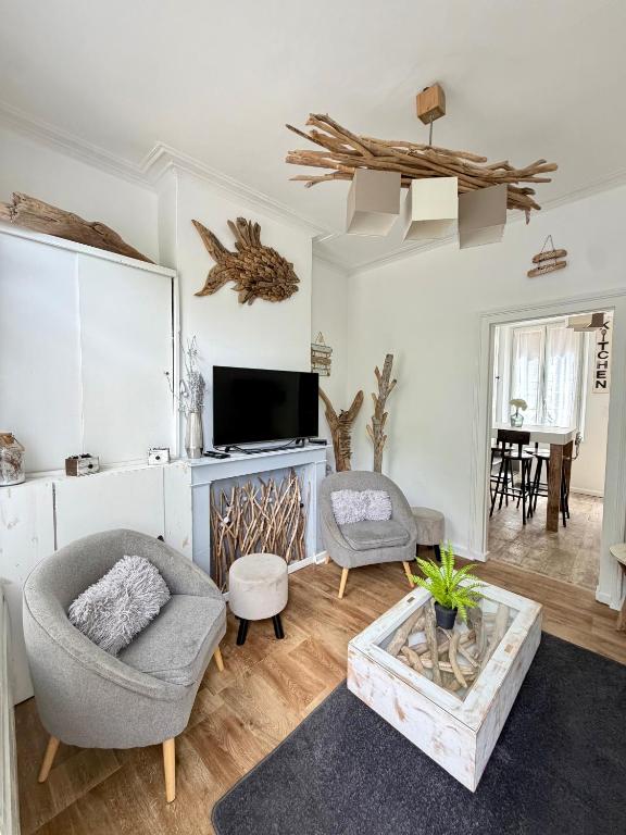 a living room with two chairs and a tv at La Maison Du Bois Flotté in Boulogne-sur-Mer