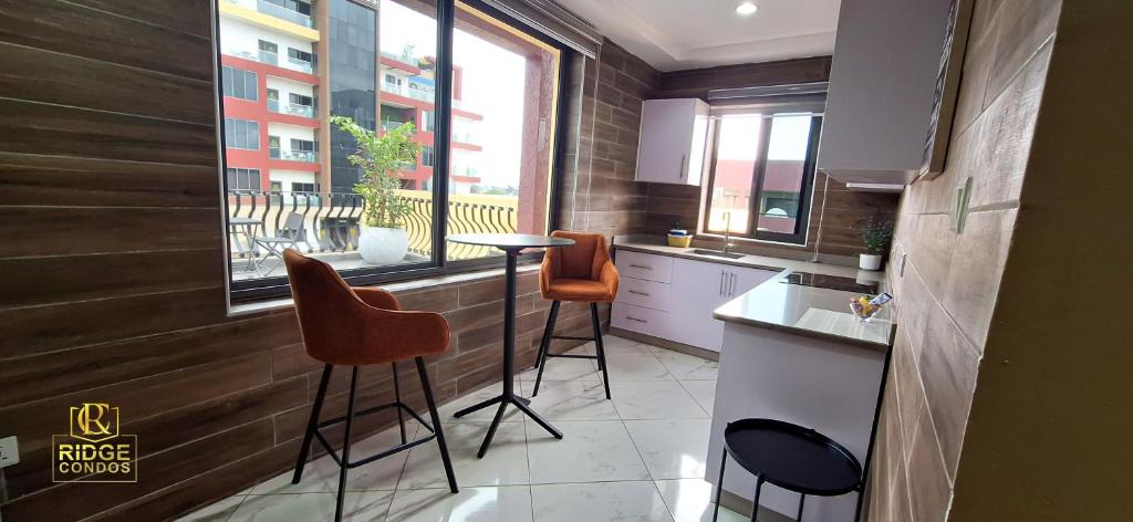 a kitchen with two stools and a table and a window at Ridge Condos Hotel - Phase Three in Kumasi