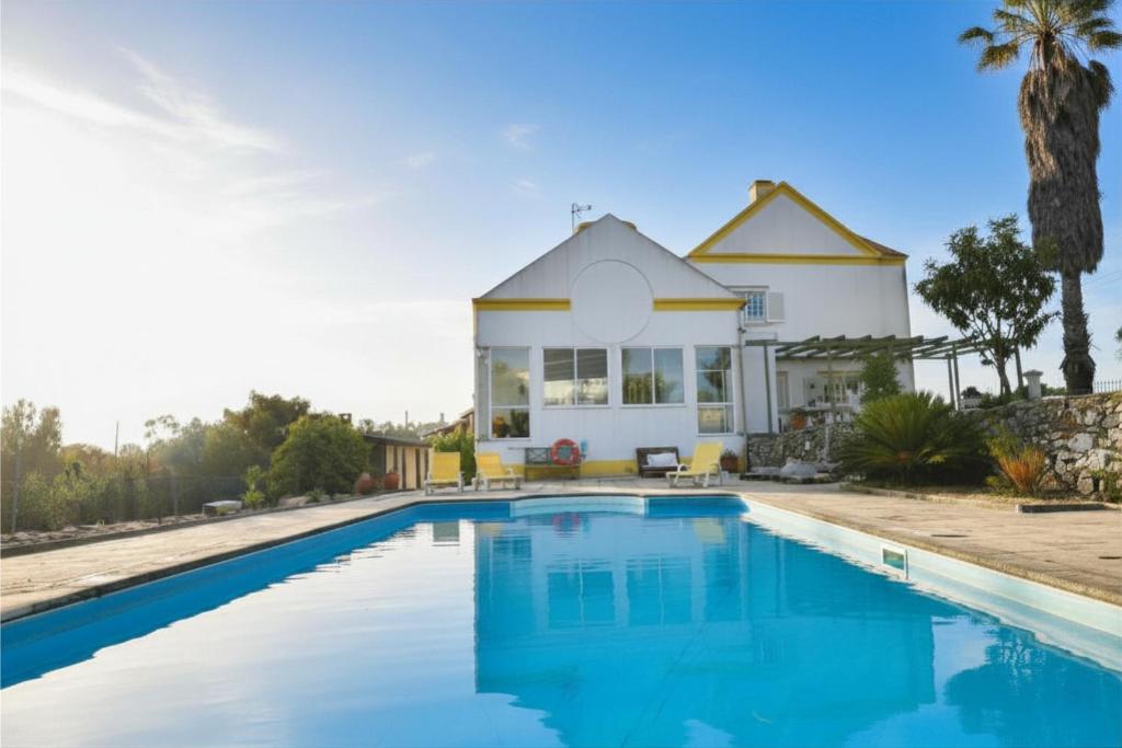 a villa with a swimming pool in front of a house at Casa do Sol Wellness Villa in Óbidos