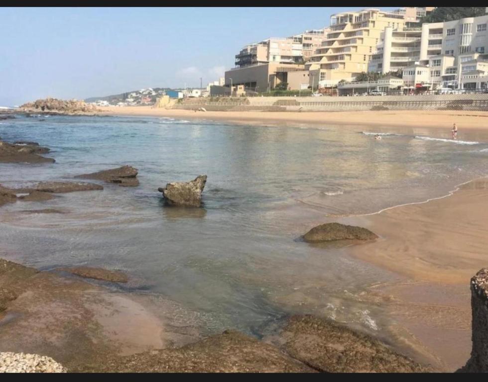 a beach with rocks in the water and buildings at 94 Camarque Umdloti in Umdloti