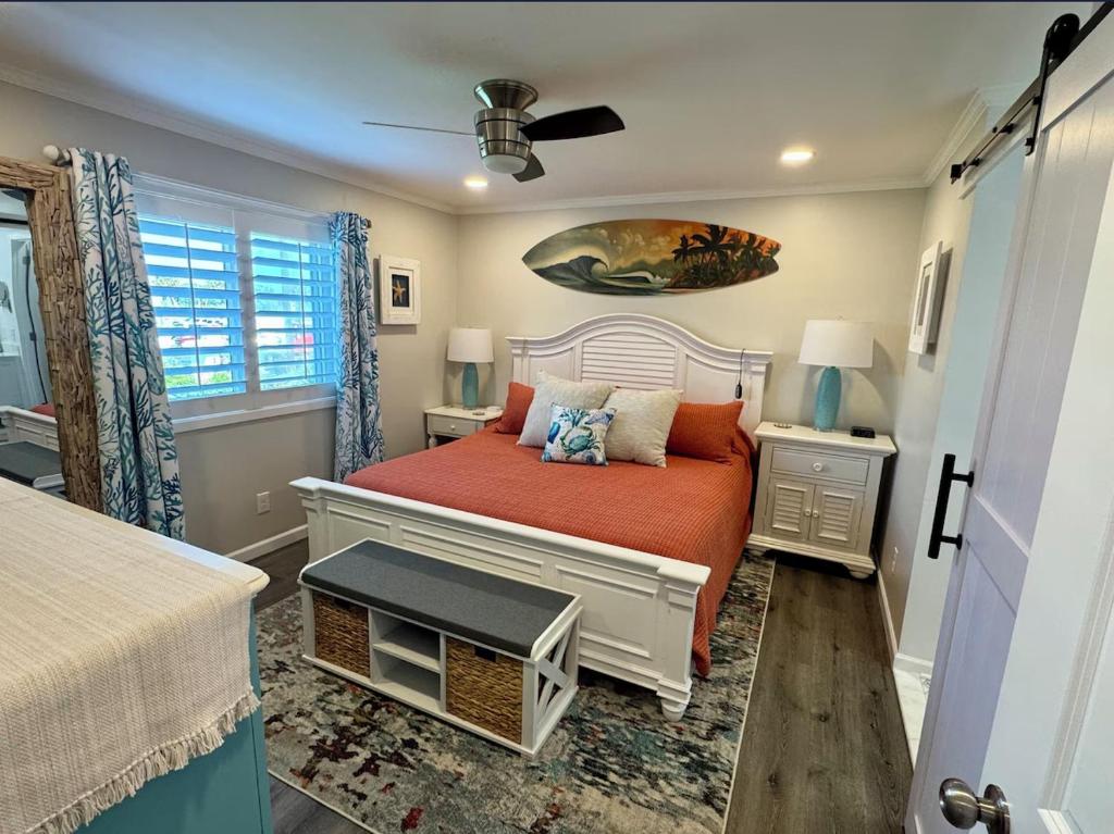 a bedroom with a bed with orange sheets and a window at Caribbean LYMM Cottage in Carolina Beach