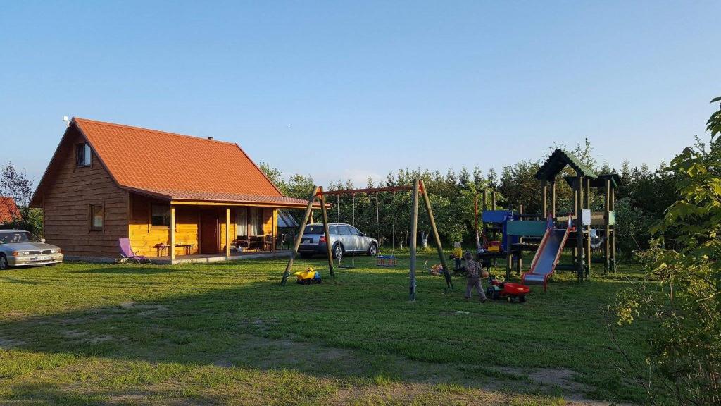 a yard with a playground with a house and a car at Mazurskie Wzgórze in Rydzewo