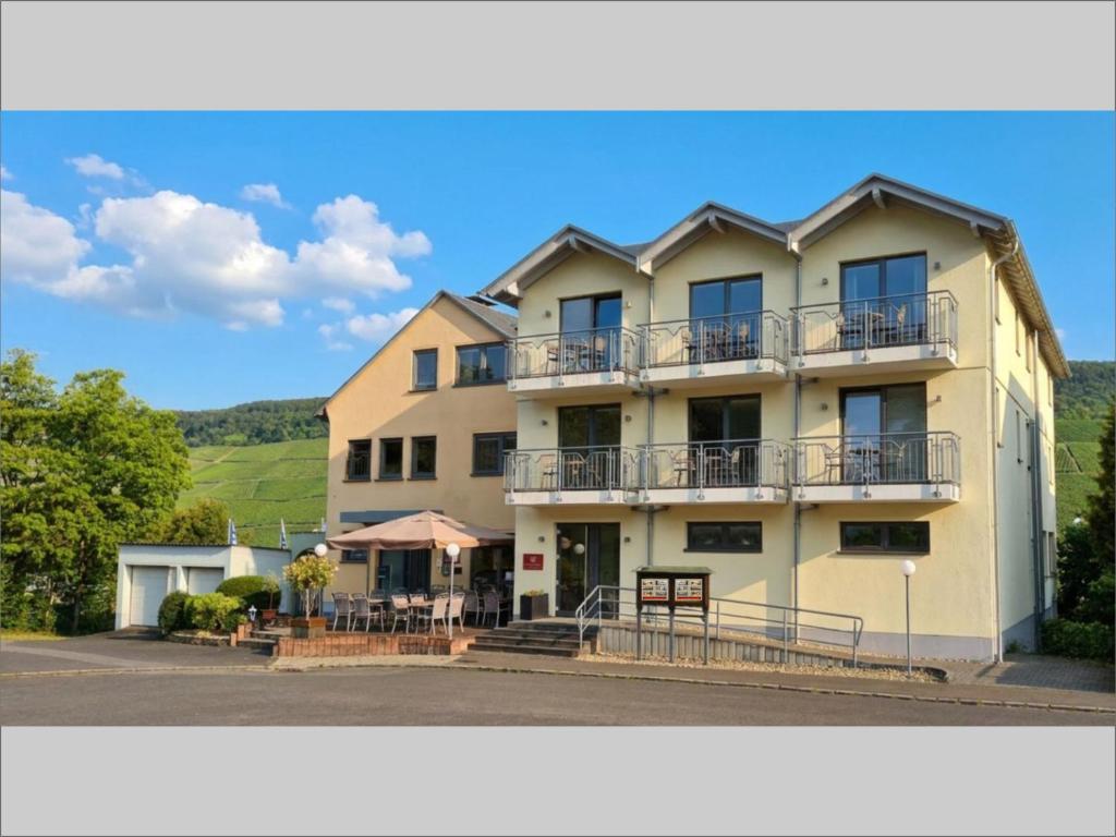 ein großes weißes Gebäude mit Balkonen und Tischen in der Unterkunft Christiana's Wein & Art Hotel in Bernkastel-Kues