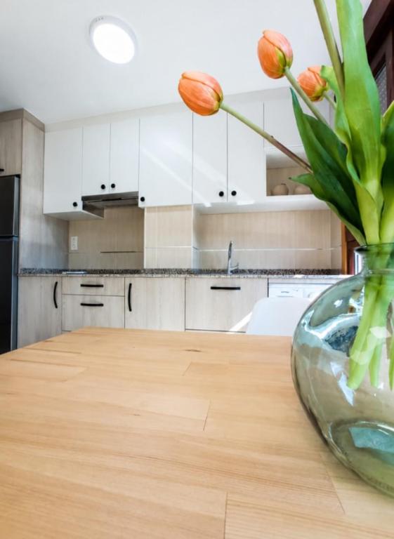 a vase of flowers on a wooden table in a kitchen at Apartamento Alfa in Monforte de Lemos