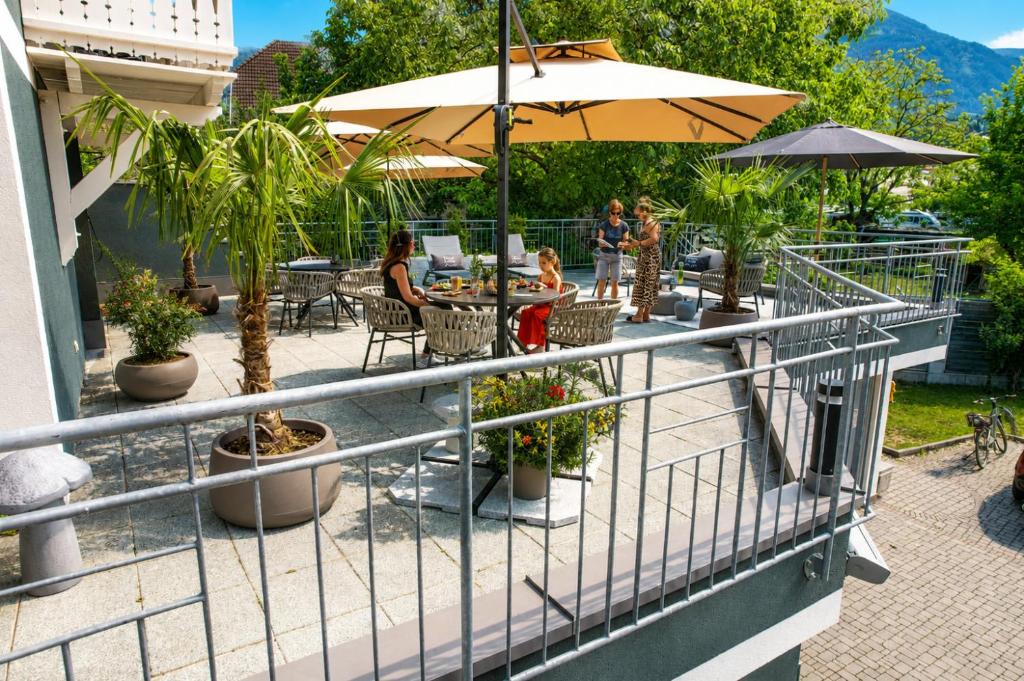a balcony with people sitting at a table with an umbrella at Pension Linder in Seeboden