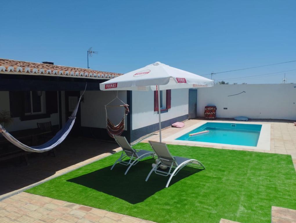 a patio with two chairs and an umbrella next to a pool at Casa dos Avós in Mértola