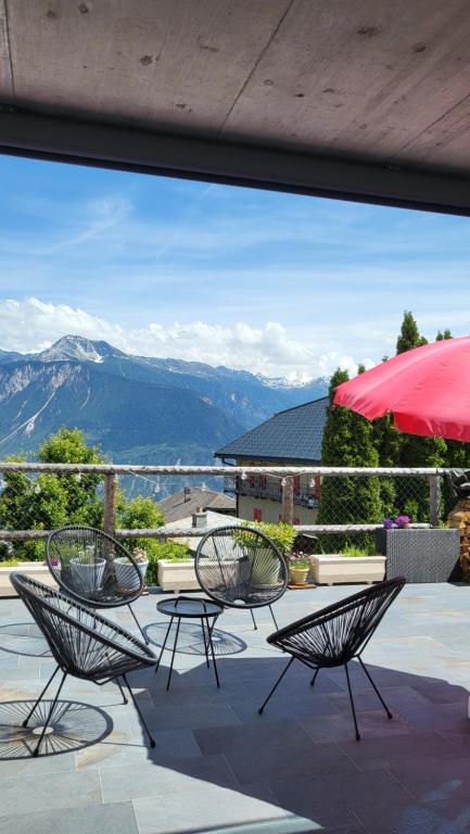 a group of chairs and an umbrella on a patio at Appartement Randogne avec grande terrasse in Crans-Montana