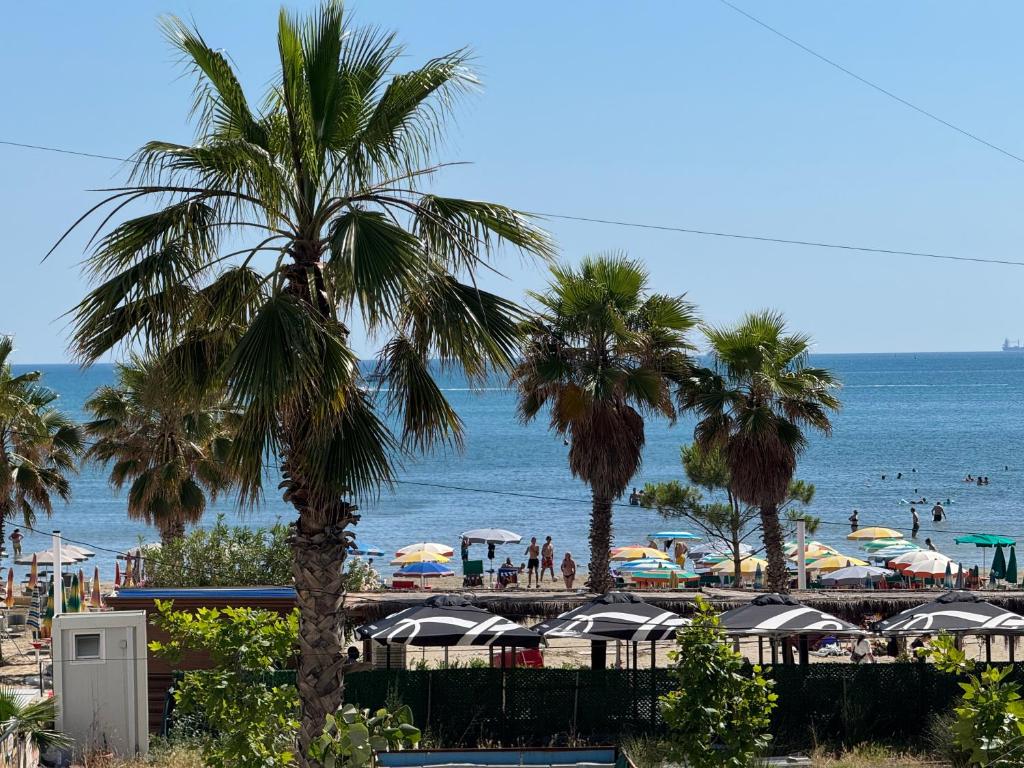 a view of a beach with palm trees and umbrellas at Casa Del Sol Seaside Hotel in Durrës