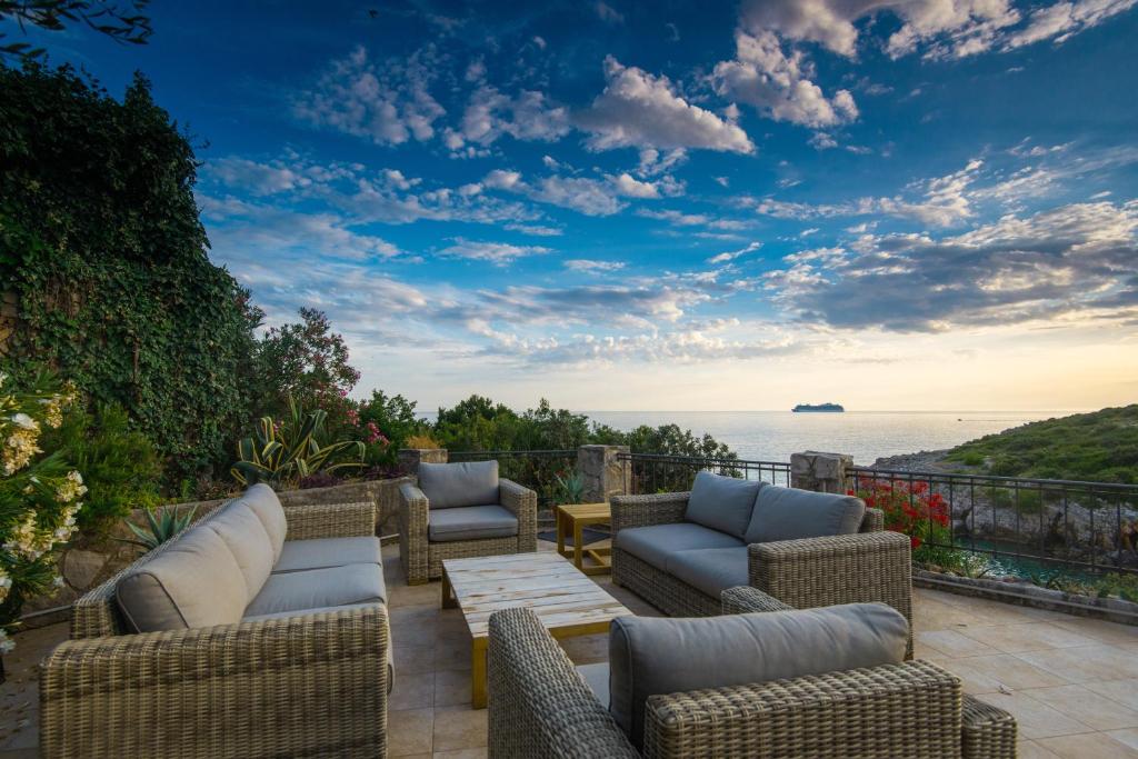 a patio with chairs and tables and a view of the ocean at Vila Veslo in Begovići