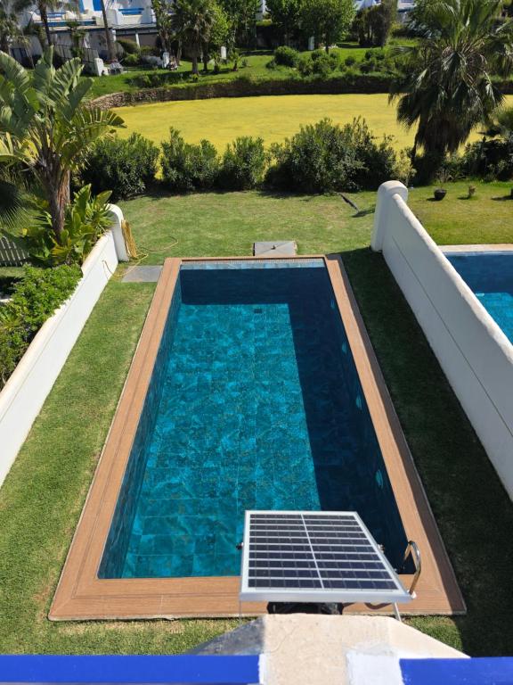 a swimming pool with a solar panel in the grass at Private villa with pool in Bouznika