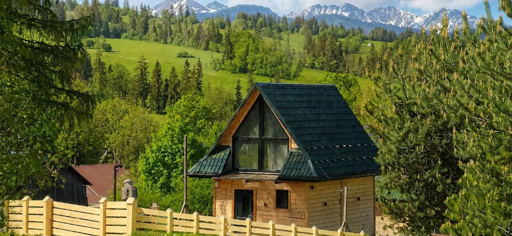 a wooden house with a fence and mountains in the background at Domek w Tatrach - Osada Ostrysz in Dzianisz