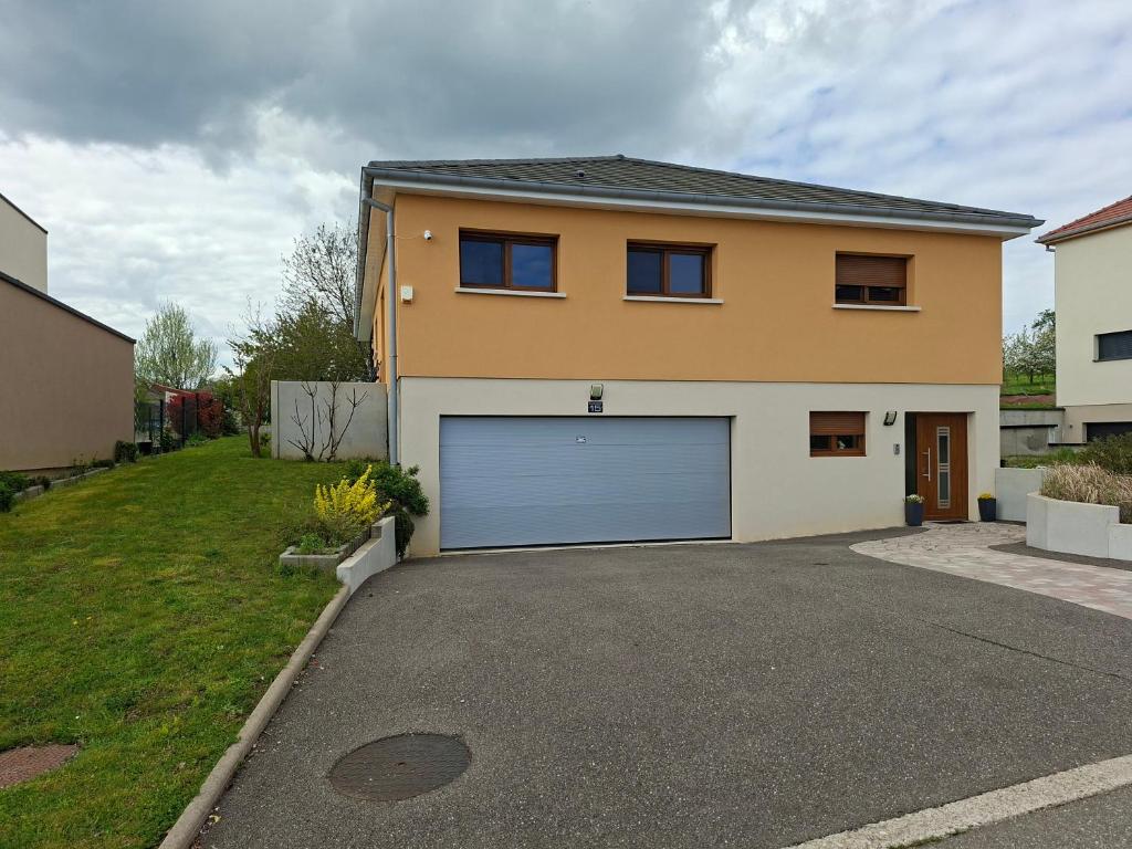 a house with a blue garage door in a driveway at Apartment Einliegerwohnung in Hagenthal-le-Haut