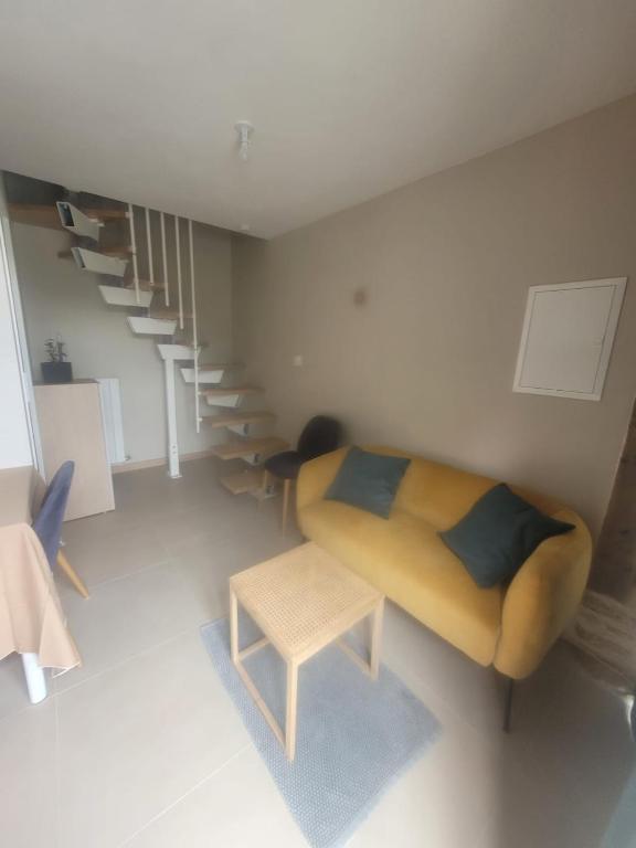 a living room with a yellow couch and stairs at Maisonnette nature et sérénité in Évran