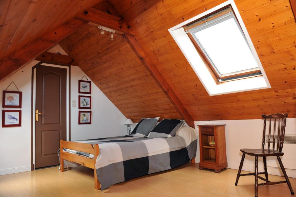 a bedroom with a large bed with a skylight at Gite de Kergrist in Paimpol