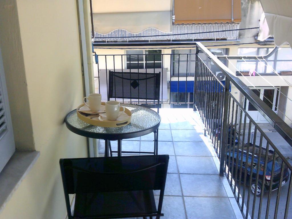 a table with two m cups on it on a balcony at ΑΚ City Apartment 1 in Ágios Rókkos