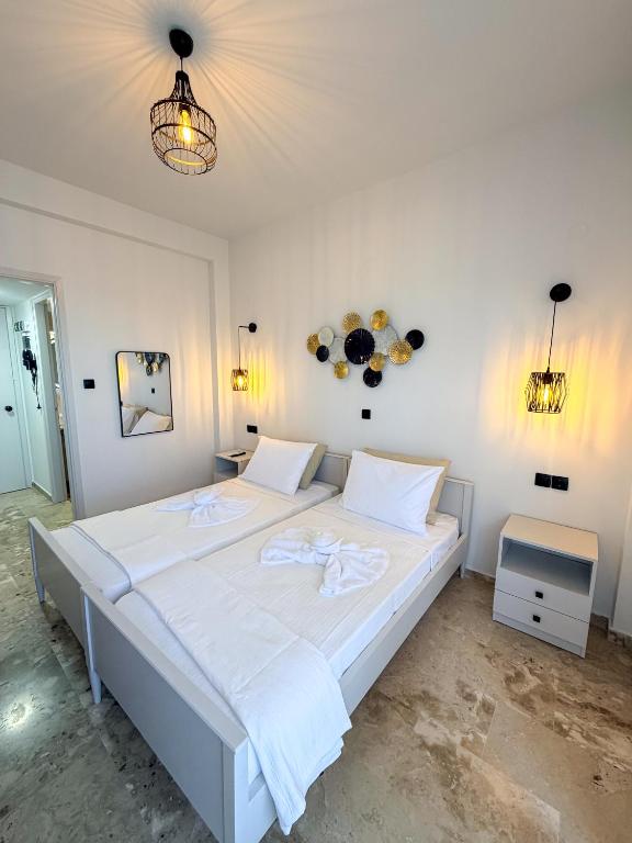 Ein weißes Schlafzimmer mit einem großen Bett und weißer Bettwäsche. in der Unterkunft Volcano Glow in Methana