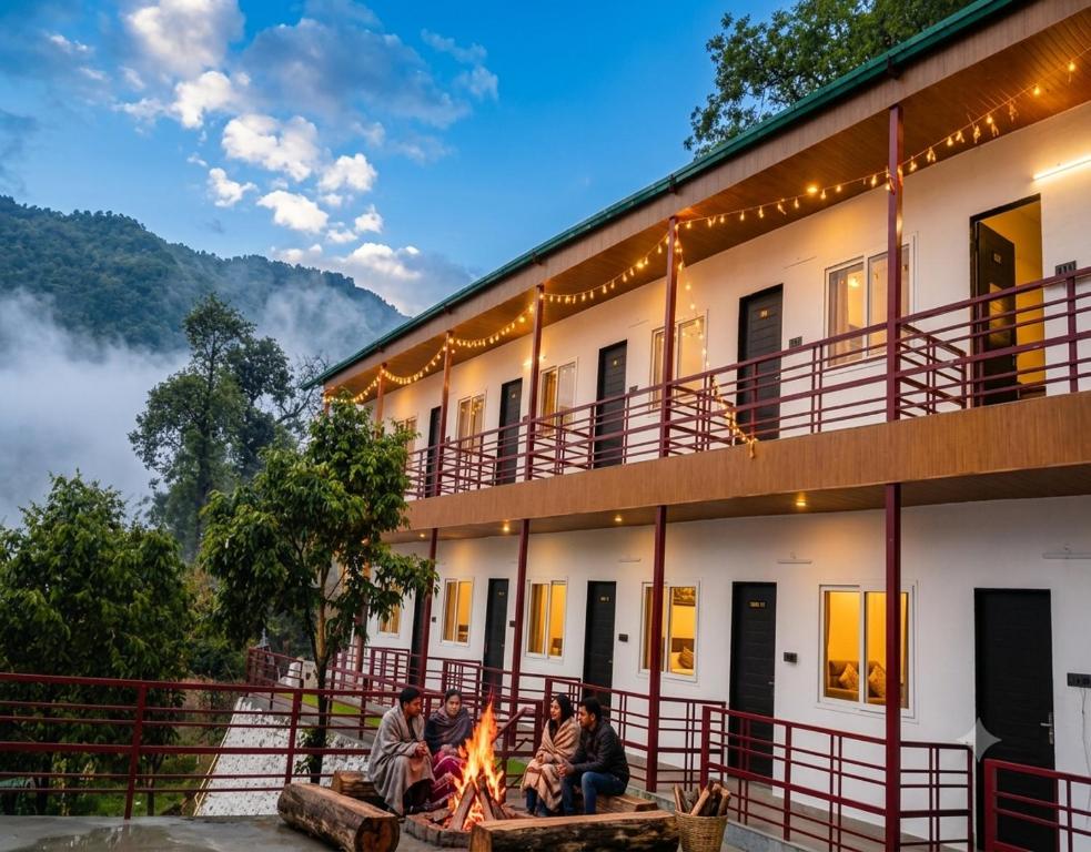 a group of people sitting around a fire in front of a building at The Chapter Stay - Kedarnath in Phata