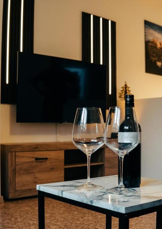 two wine glasses on a table with a bottle of wine at Ferienwohnung Salvenblick in Söll