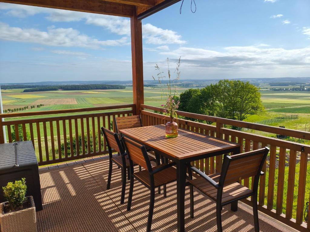 a wooden table and chairs on a balcony with a view at Morgenrot Panorama-Apartment 2 - Zwei Balkone in Gnotzheim