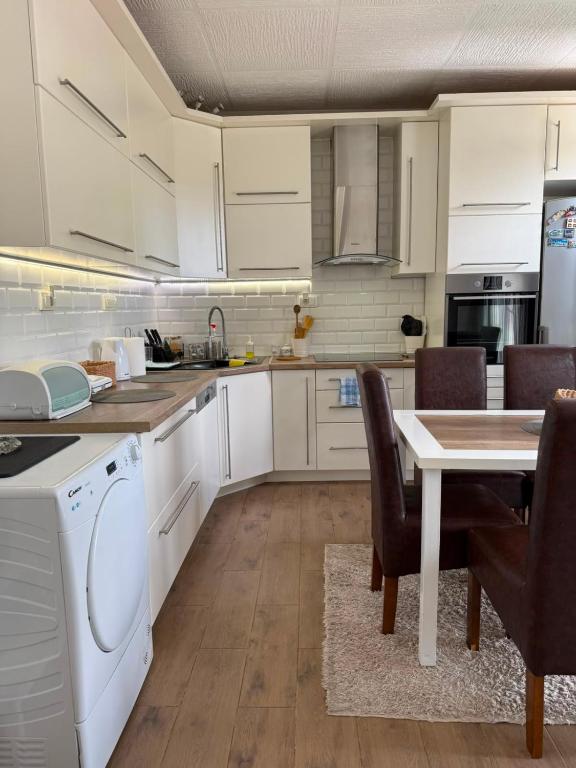 a kitchen with white cabinets and a table and chairs at Cerak lux in Bele Vode
