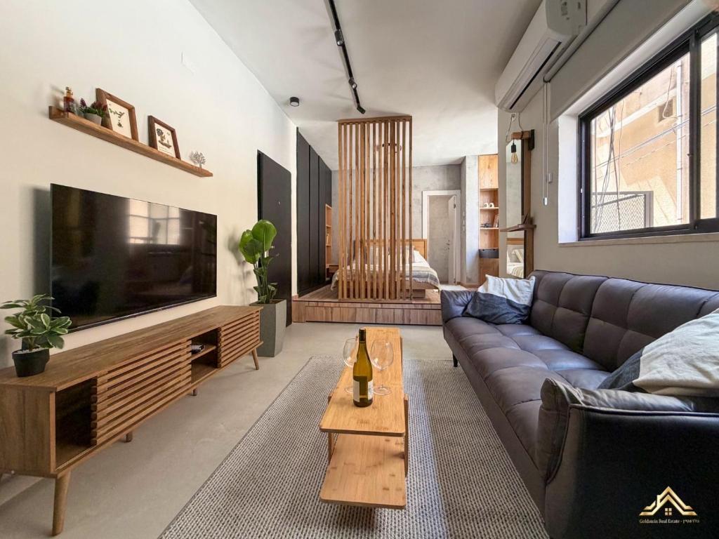 a living room with a couch and a tv at Urban Waves 1 in Netanya
