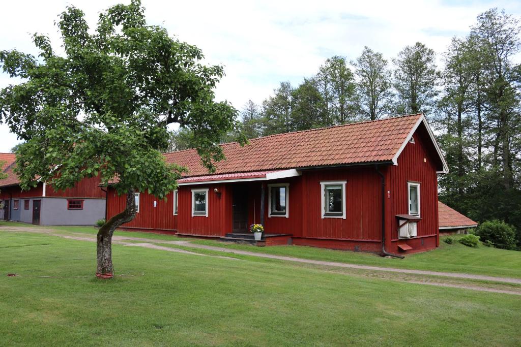 a red house with a tree in the yard at Bäckens Guesthouse in Älgarås