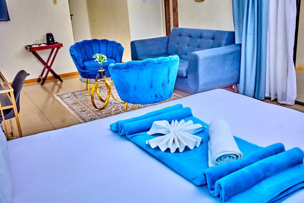 a room with a table with blue chairs and a bed at Potato Suites n Spa in Gaborone