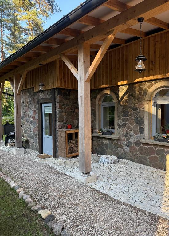 a stone house with a wooden pergola at Viesu māja Gulbji in Bigauņciems