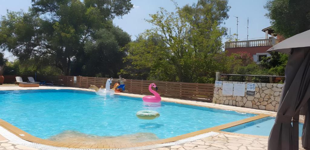 a swimming pool with two inflatable flamingos in it at Cozy 2BR Corfu – Apt 9 in Gouvia