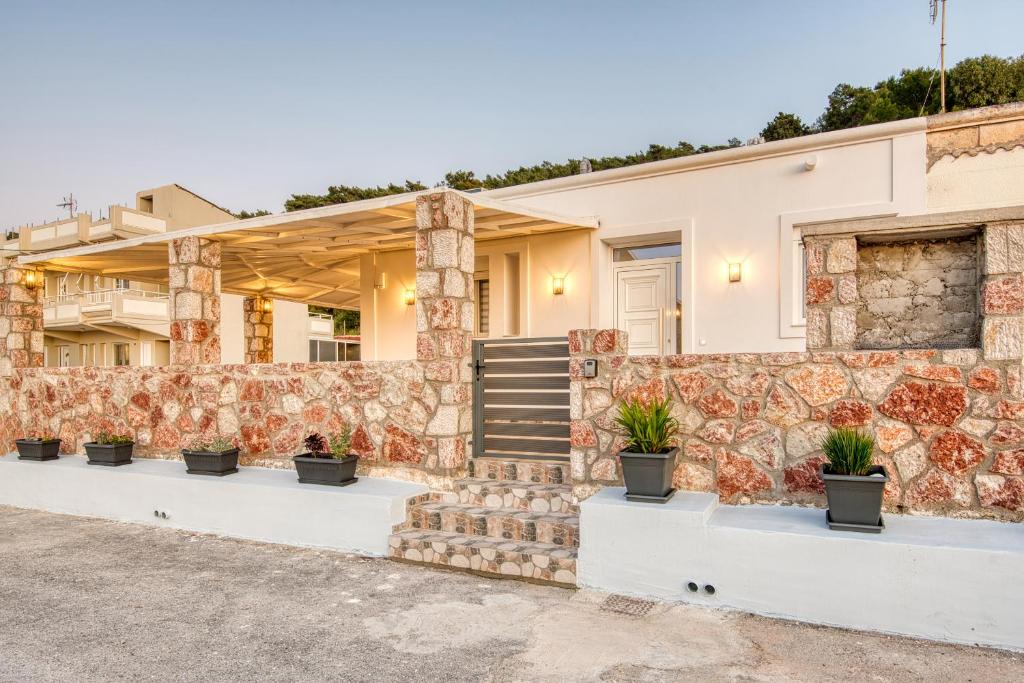 a house with a stone wall and potted plants at Floras House in Paradeísion