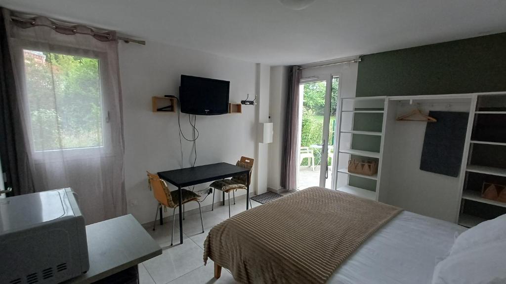 a bedroom with a bed and a desk and a television at Le Cozy Cocon in Franqueville-Saint-Pierre