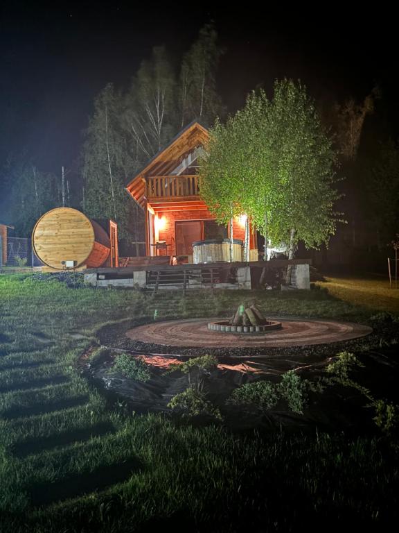 a log cabin with a fountain in the yard at night at Rumelówka in Wawrowice