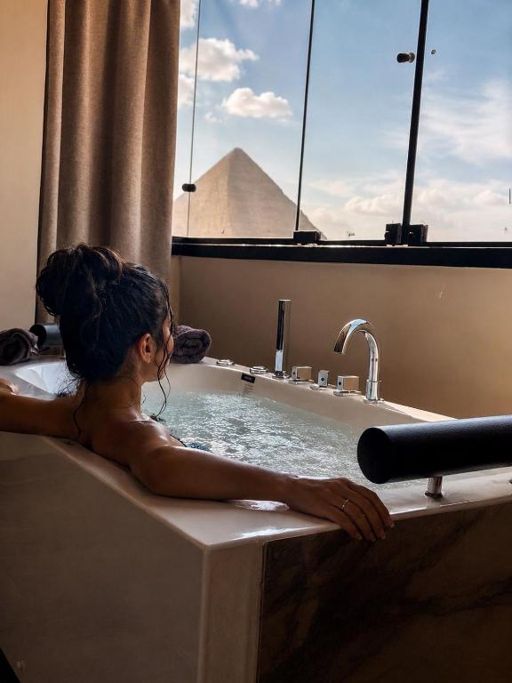 a woman in a bathtub with a pyramid in the background at Pyra King Royal Pyramids Hotel in Cairo
