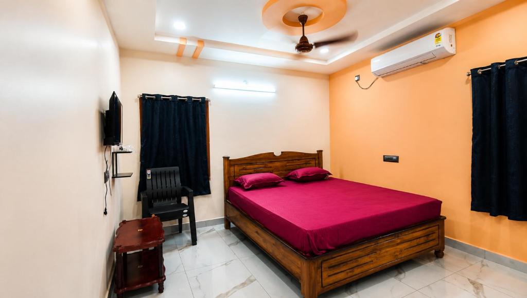 a bedroom with a wooden bed with red sheets at Sai krishna residency in Pithāpuram