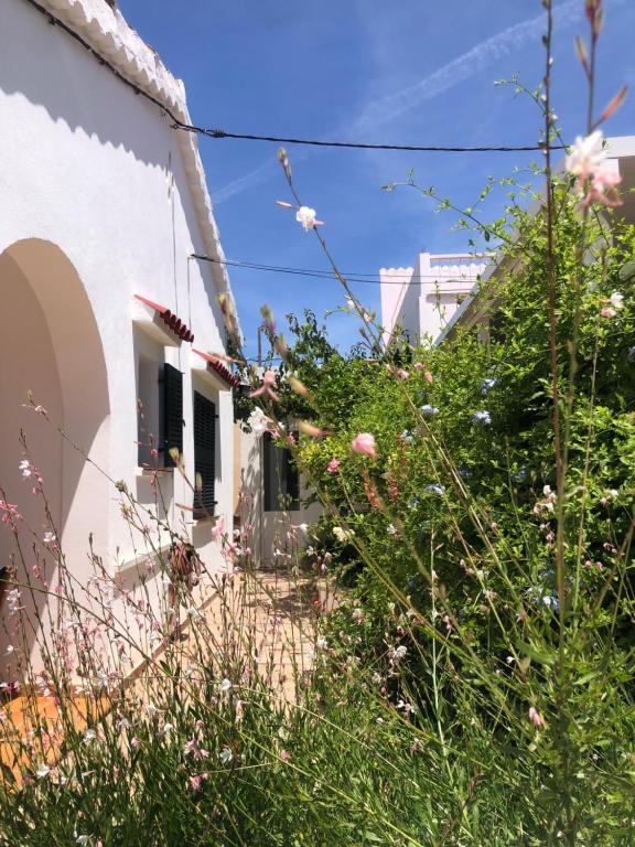 a white house with flowers in front of it at Casa Típica Ciutadella centro in Ciutadella
