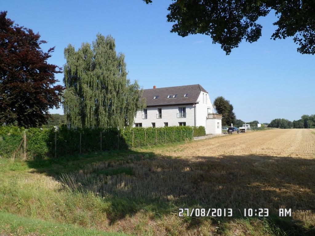 a white house with a tree next to a field at Gästehaus Brinkmann am Moor in Spenge