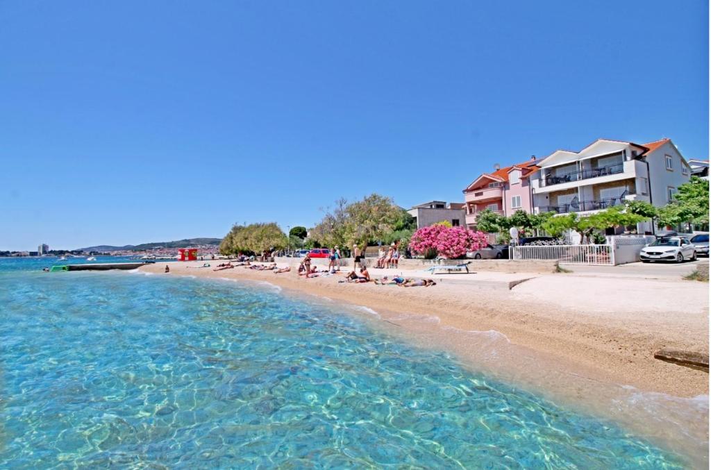 a beach with people laying on the sand and the water at Apartments Aurelia in Vodice
