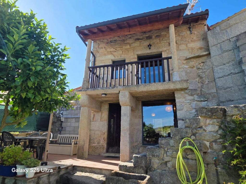 a stone house with a balcony and a door at La casa de arriba in Ourense