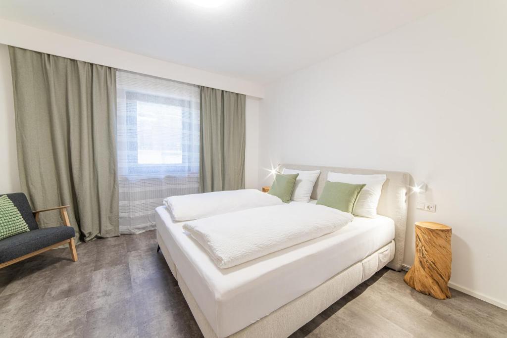 a white bedroom with a white bed and a chair at Moar Apartments in Silandro