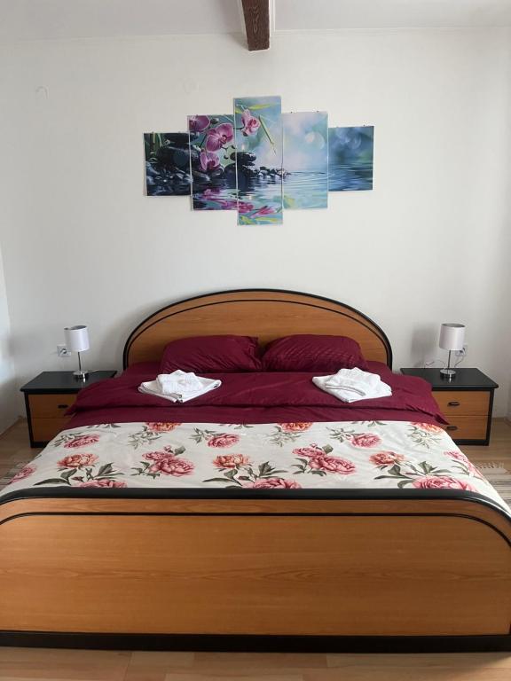 a bedroom with a bed with two lamps and two pictures on the wall at Orchidea Apartman in Bačka Topola