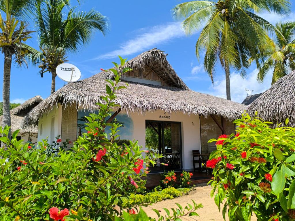 a cottage on the beach with palm trees at Long Beach Resort, Nosy Be in Nosy Be