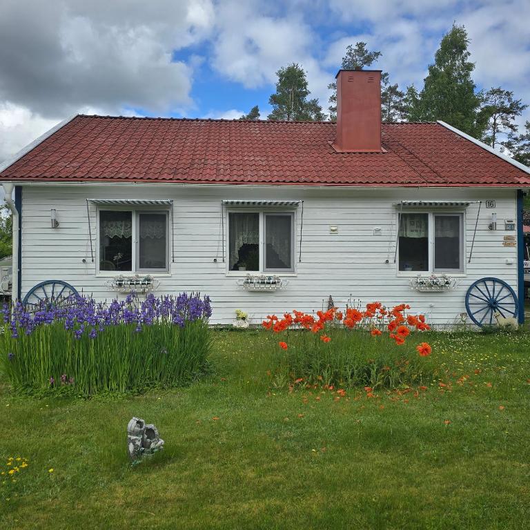 a white house with flowers in front of it at Stuga Ani Wellness & Sauna in Svartå