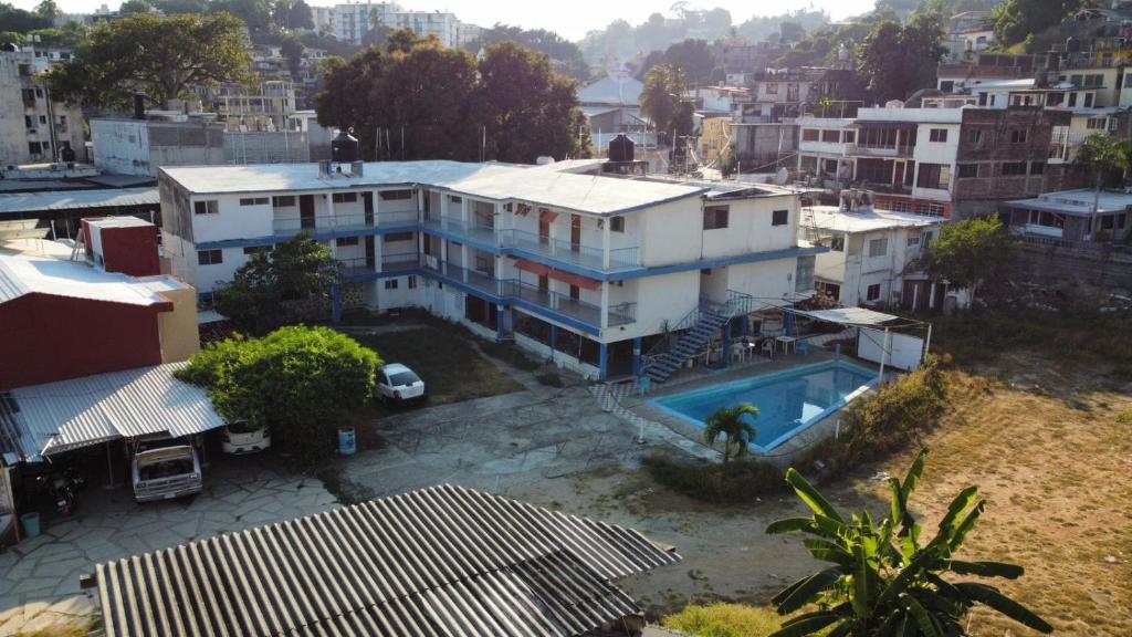 a large white house with a swimming pool in a city at Hotel Caleta Bor Acapulco in Acapulco