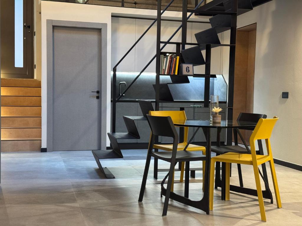 a dining room with a black table and yellow chairs at Atelier Volturno in La Maddalena