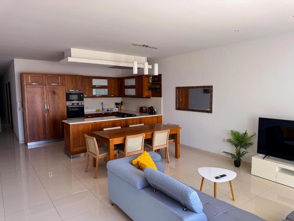 a living room with a blue couch and a kitchen at Marsaxlokk Harbour View Apartment in Marsaxlokk