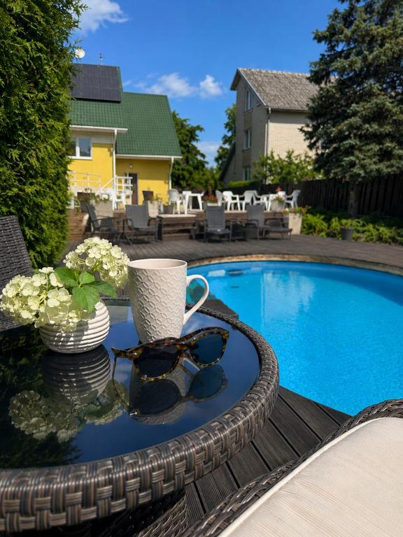 a table with sunglasses on it next to a swimming pool at Saulės Namai in Palanga